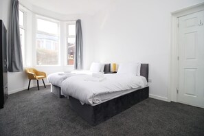 A bedroom with a large bed, a chair, and a window. - Rugby Road by Tŷ SA (Newport)