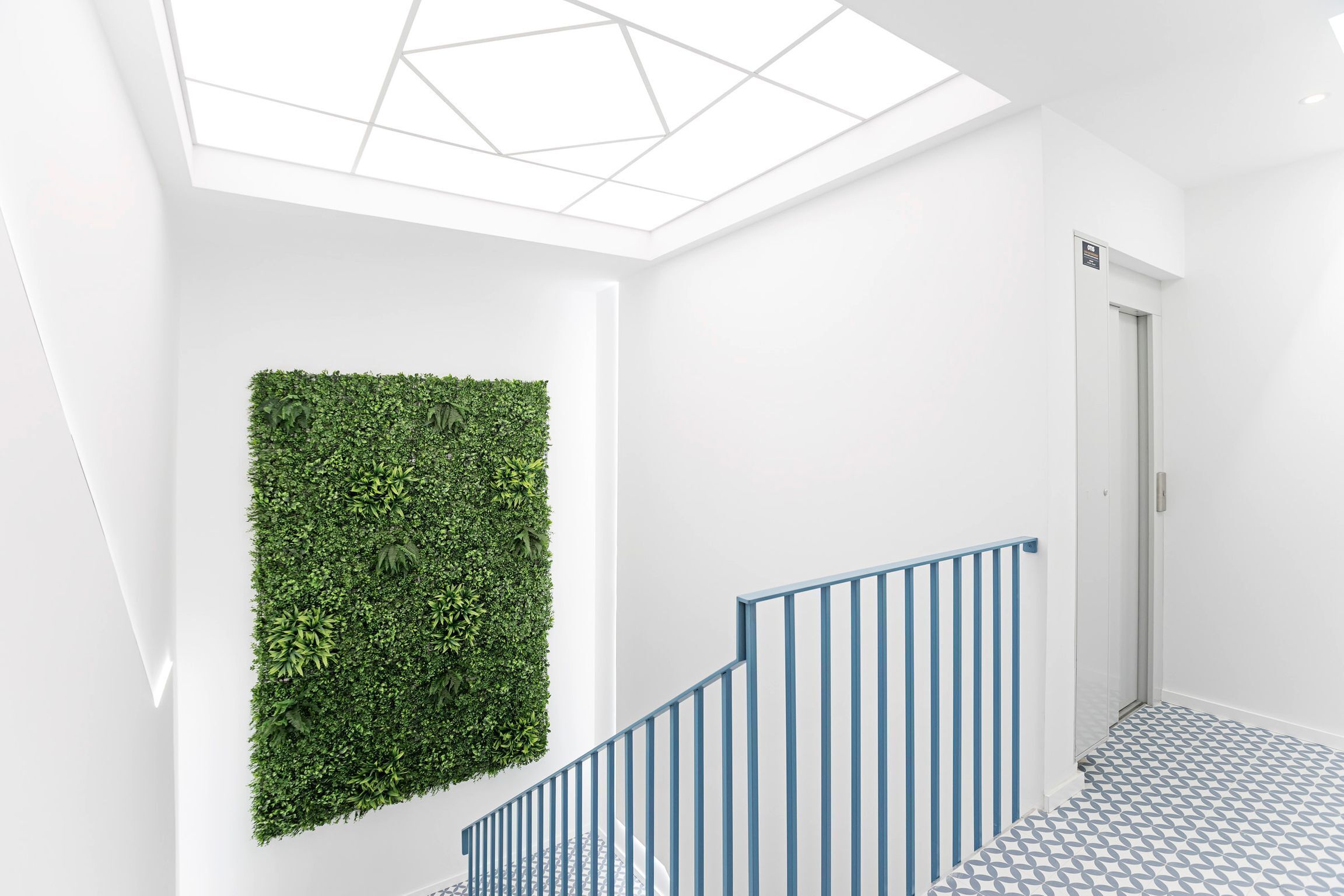 Ein modernes Interieur mit einer Treppe, einer Glasdecke und einer grünen Wand.