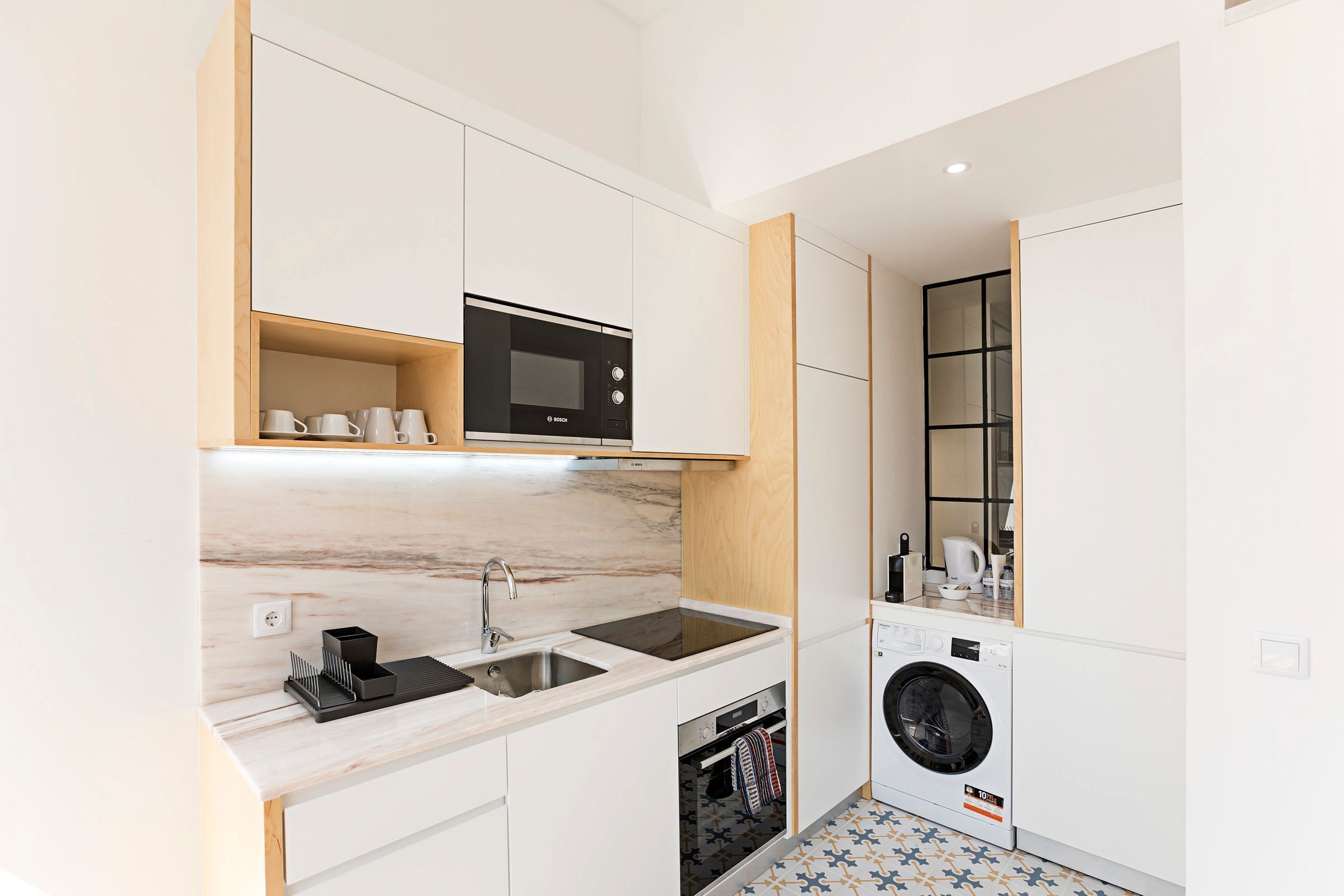 A compact kitchen with a microwave, sink, and built-in washing machine.