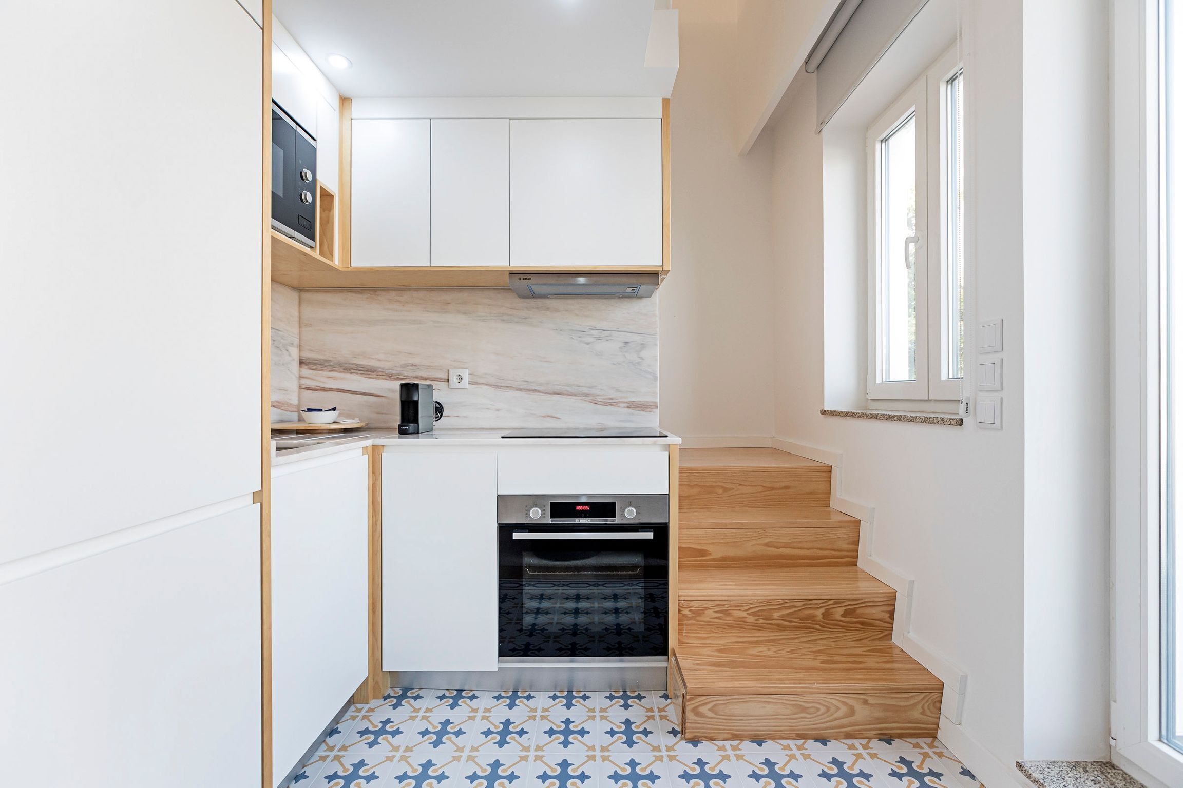 A compact kitchen with white cabinets, a built-in oven, and a patterned floor.