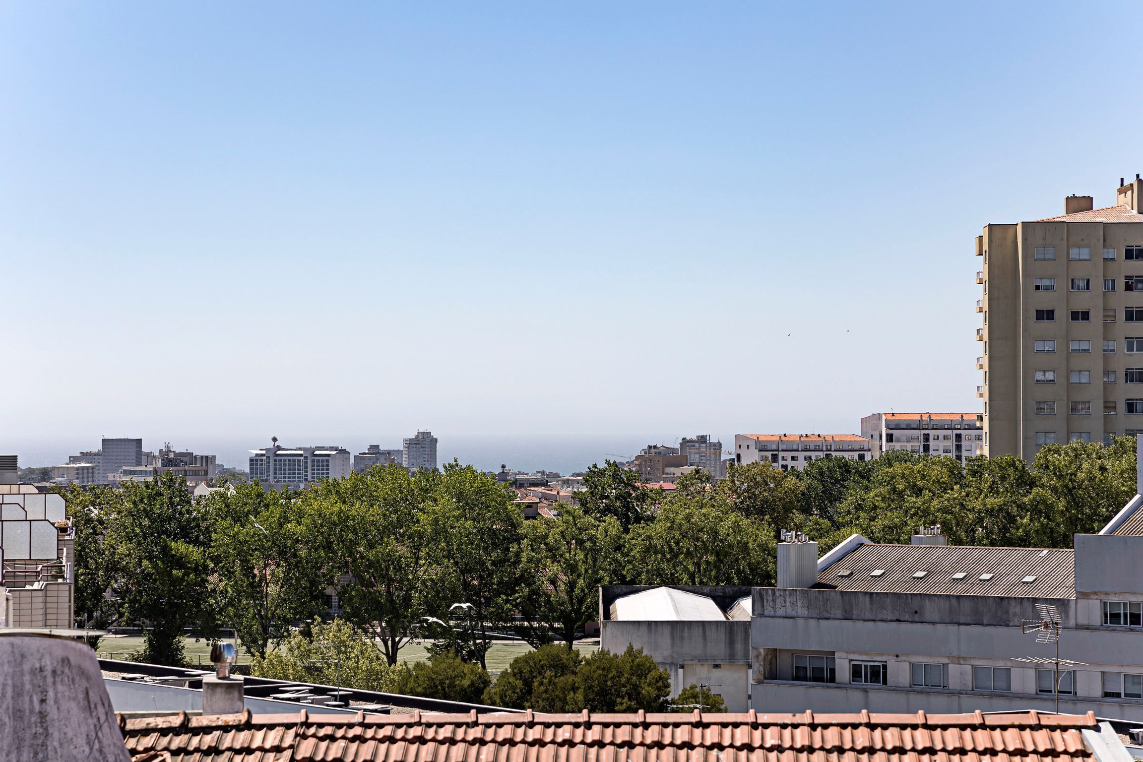 A cityscape with a prominent building in the foreground, a clear sky, and distant buildings.