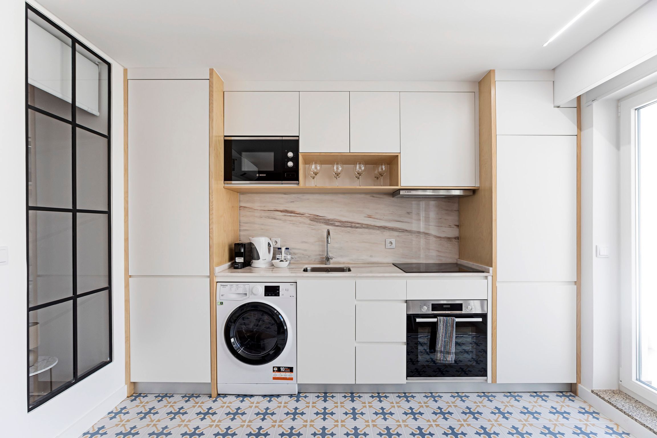 A compact kitchen with a washing machine, microwave, and oven.