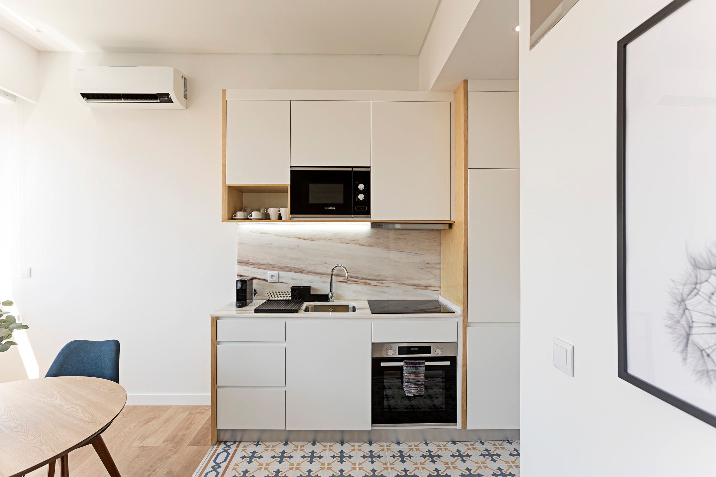 A modern kitchen with white cabinets, a built-in microwave, a sink, and an oven.