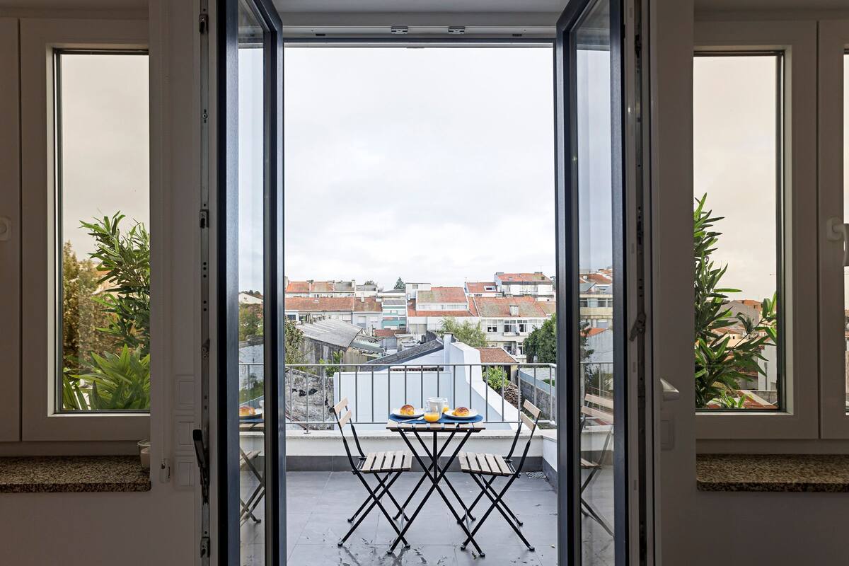 A balcony with a table and chairs, overlooking a residential area.