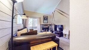 Una sala de estar acogedora con un sofá de cuero, una pequeña mesa de madera, una chimenea y un televisor.