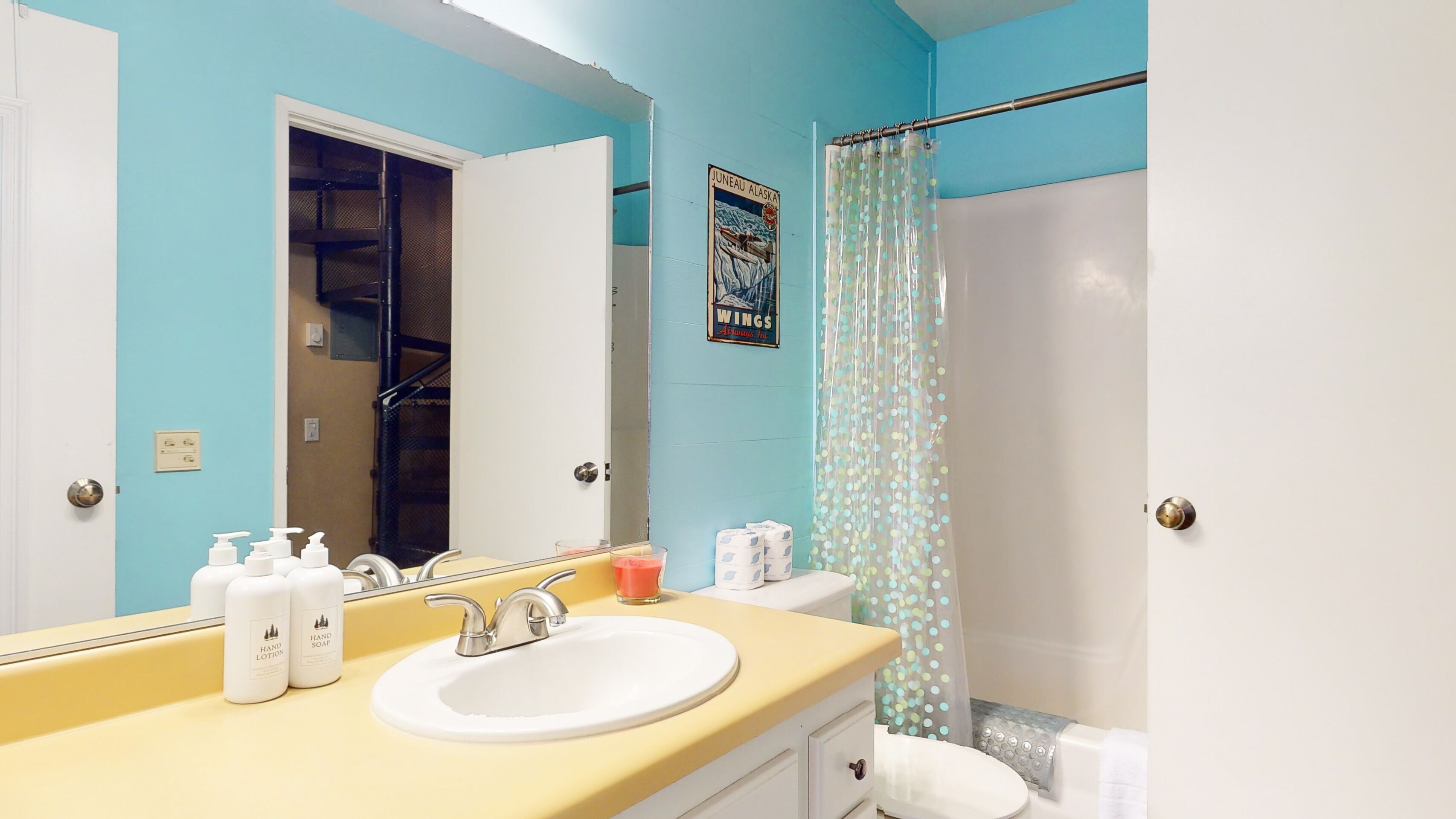 A bathroom with a sink, mirror, and shower curtain.
