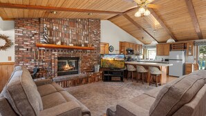 A cozy living room with a fireplace, comfortable seating, and a kitchen area with modern appliances.