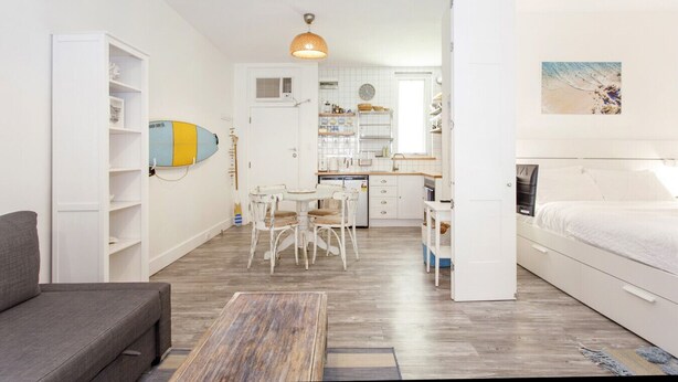 A compact living space with a kitchenette, dining area, and a bedroom. - Beach Shack Fremantle (Fremantle)