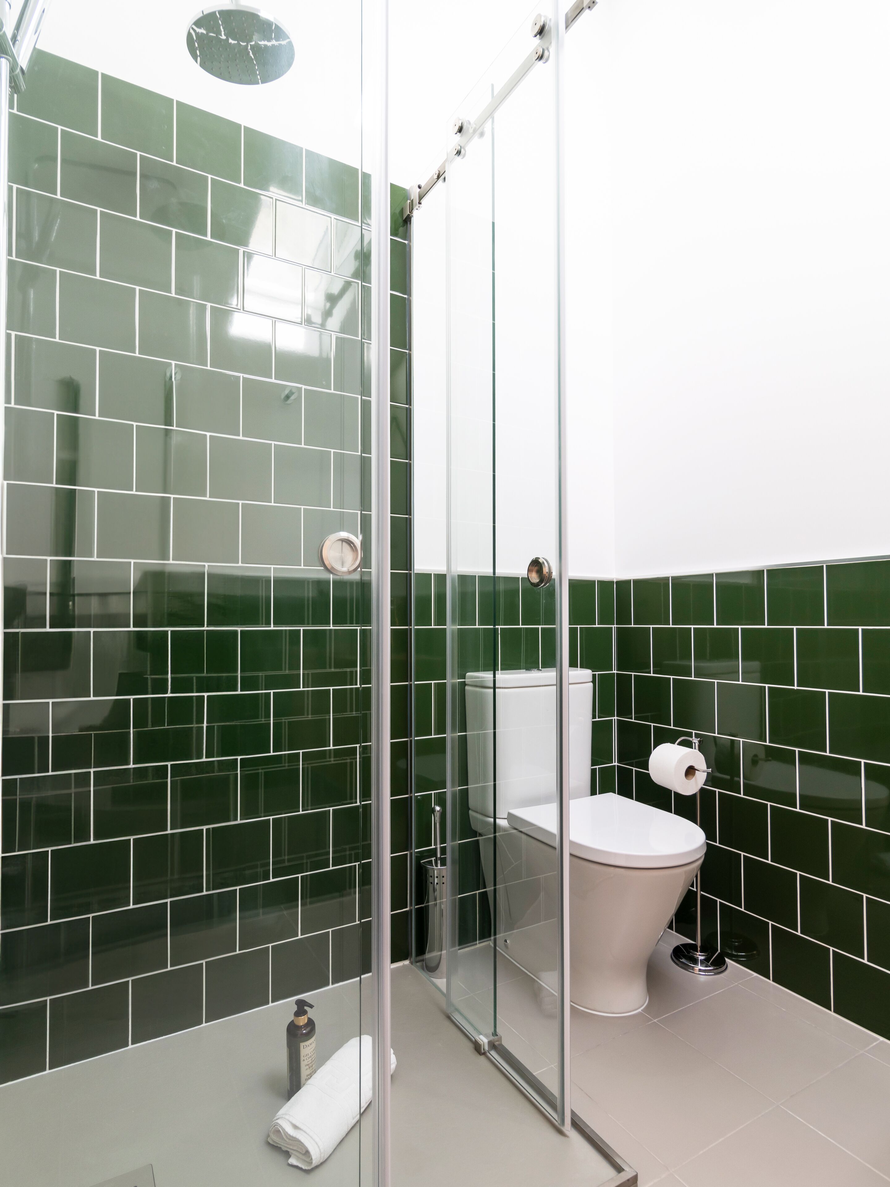 A modern bathroom with a glass shower enclosure, a toilet, and a sink.