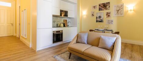 Un espace de vie compact comprenant un coin cuisine, un canapé et un coin repas.