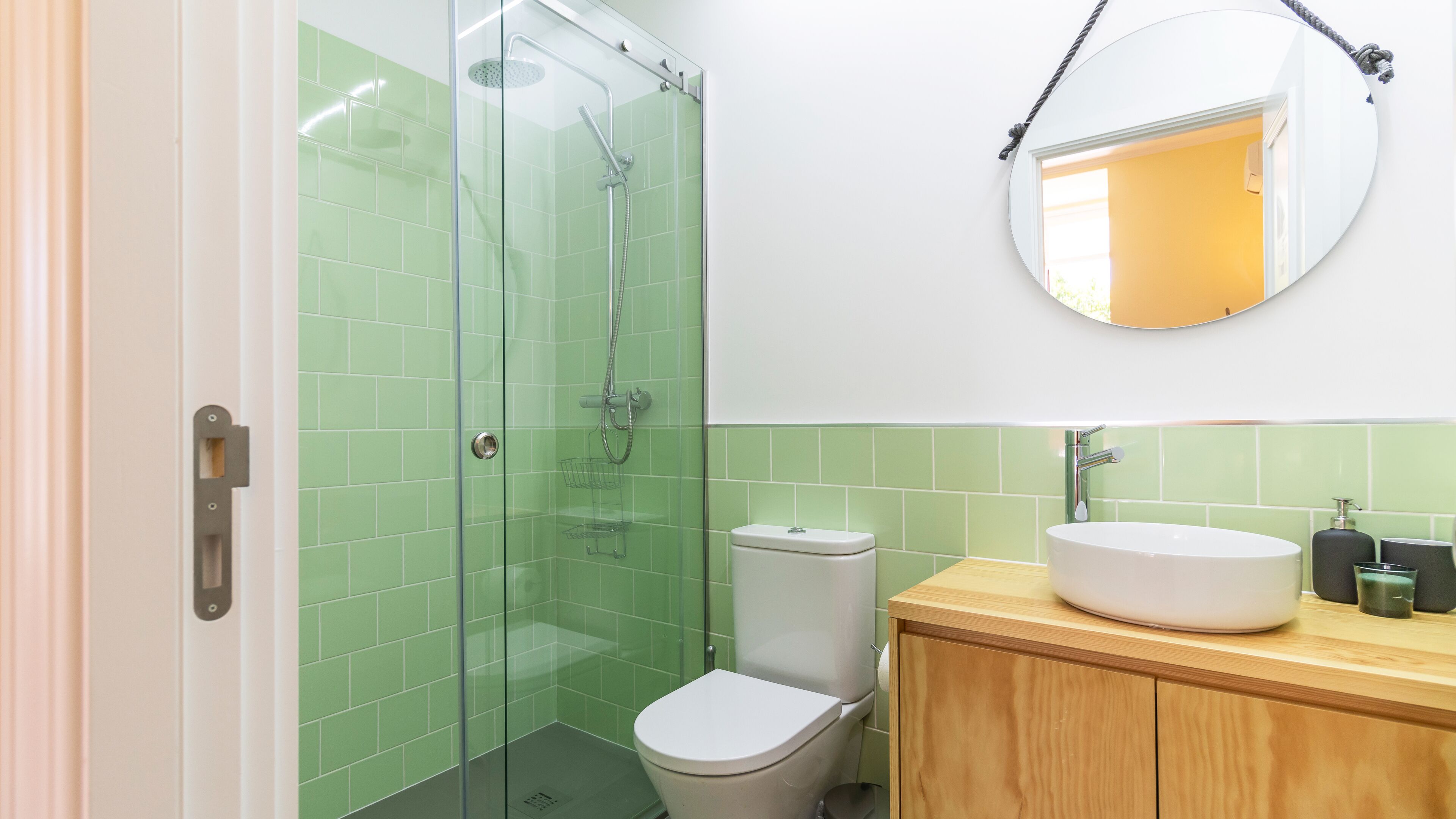 Une salle de bain avec une douche à parois de verre, des toilettes et un meuble-lavabo en bois avec un évier.