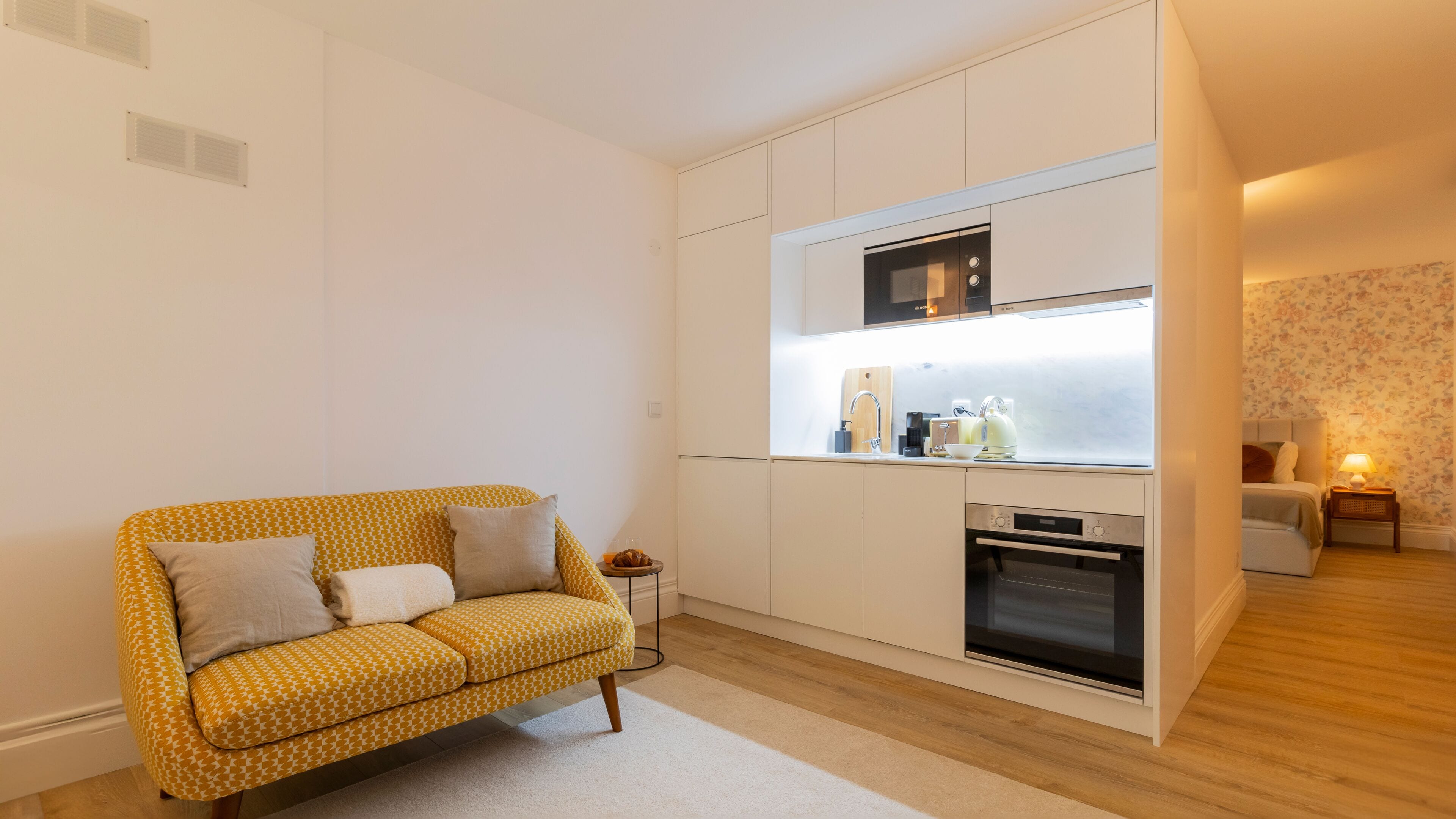 A compact living space with a kitchenette, a sofa, and a small dining area.