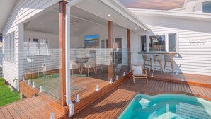 A covered outdoor deck with a pool, glass balustrades, and seating areas. - Bohemian Coastal Dream (Port Macquarie)