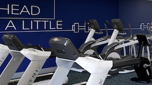 A gym with treadmills and stationary bikes, a blue wall with motivational text, and a ceiling with fluorescent lights. - Holiday Inn Express & Suites Dayton Highway 90 by IHG (Dayton)