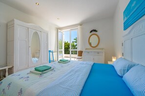 Un dormitorio con una cama grande, un armario, un espejo y vistas al exterior.