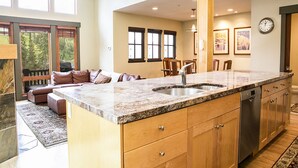 A kitchen with a granite countertop, stainless steel sink, wooden cabinets, and a dishwasher.