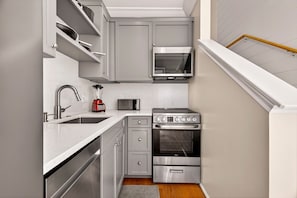 A compact kitchen with a built-in oven, microwave, and stainless steel appliances.