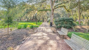 A paved pathway in a park with trees and a bench. - Newly Built Carriage House in Unbeatable Location by Lucky Savannah (Savannah)