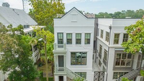 A multi-story building with a white facade, multiple windows, and a balcony. - Newly Built Carriage House in Unbeatable Location by Lucky Savannah (Savannah)