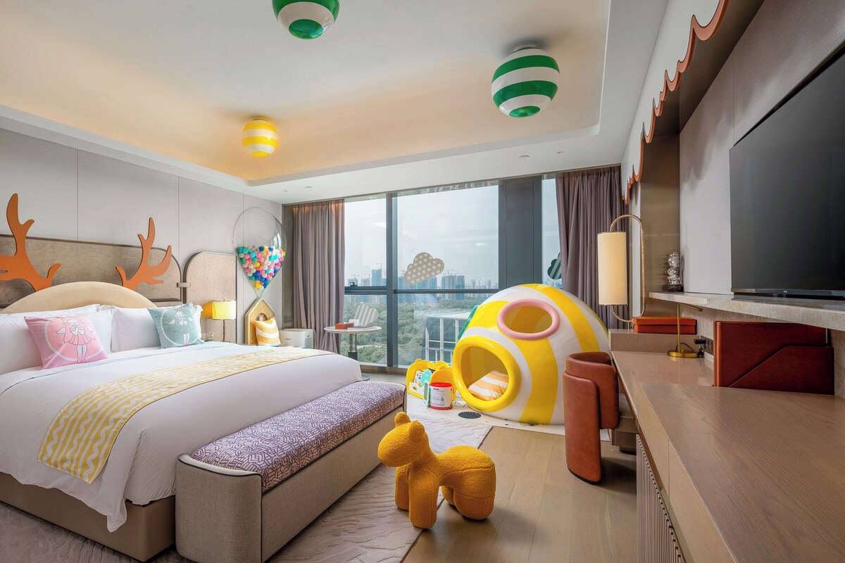 Een moderne hotelkamer met een groot bed, een bureau, een televisie en uitzicht op de stad.