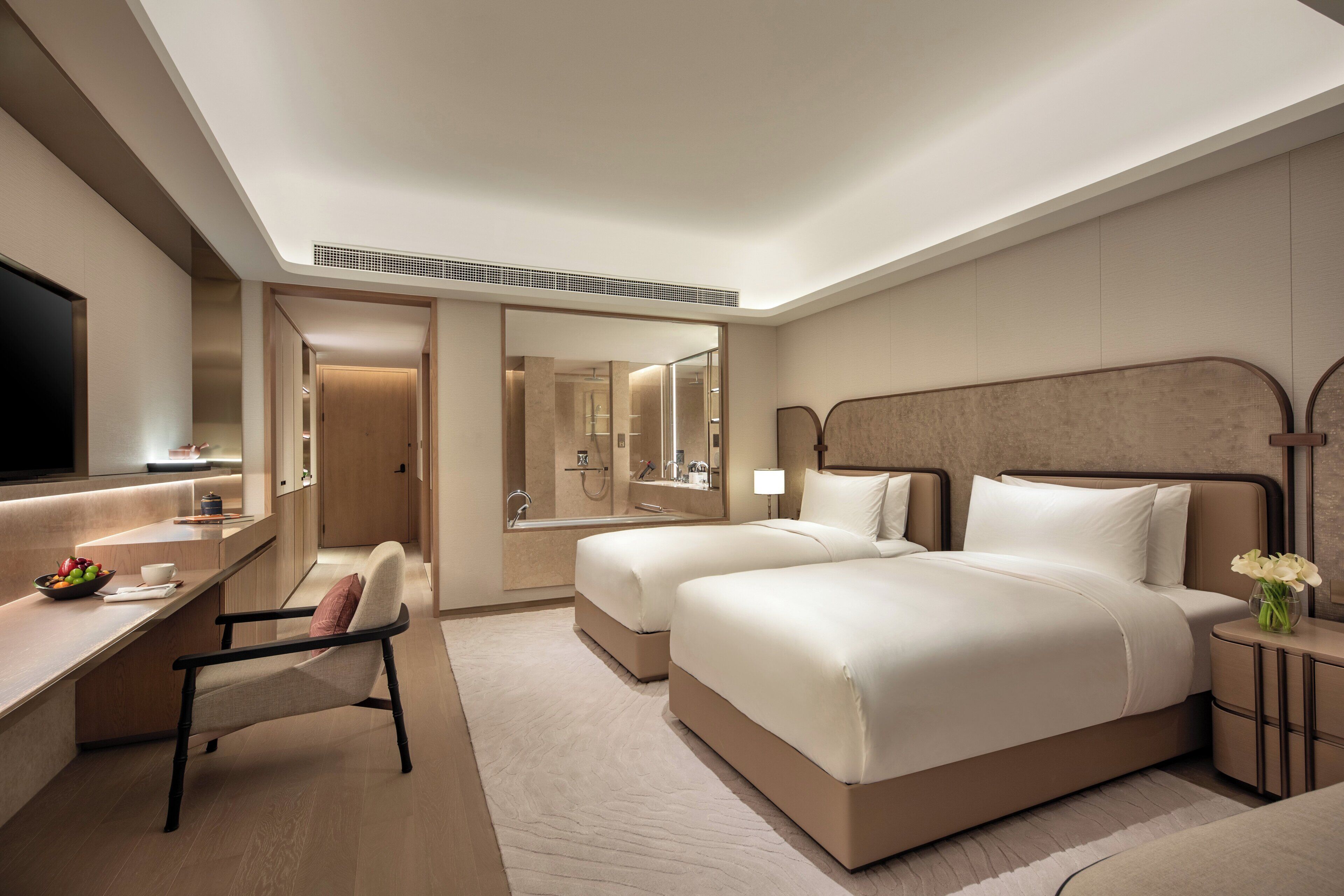 Een hotelkamer met een groot bed, een bureau met stoel, een televisie en een badkamer met douche.