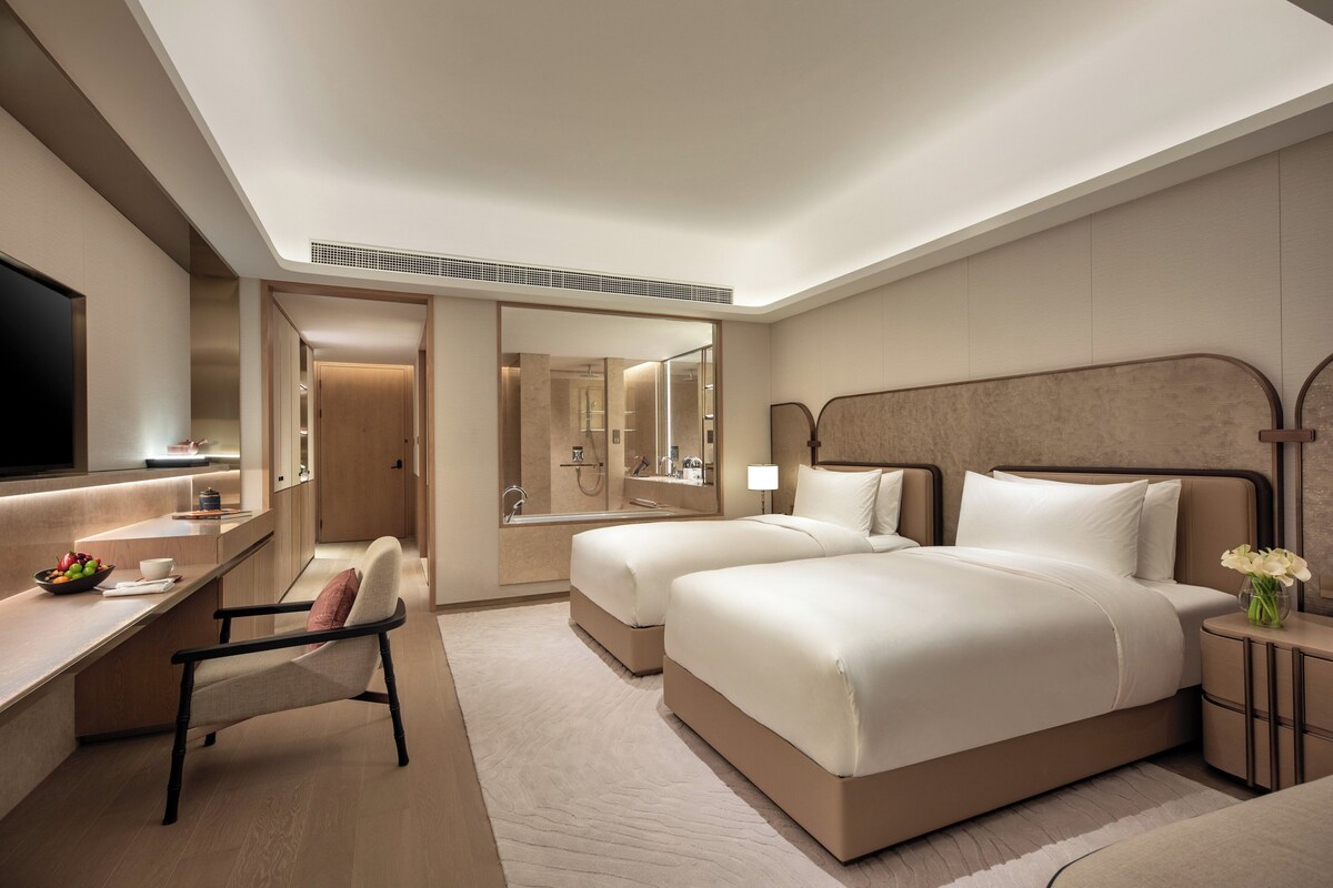 Een hotelkamer met een groot bed, een bureau met stoel, een televisie en een badkamer met douche.