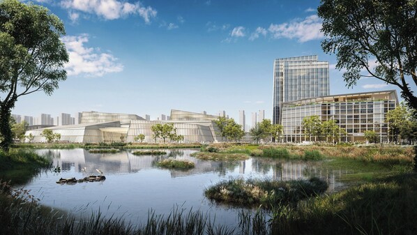 Un ensemble de bâtiments modernes, avec un plan d'eau aux reflets changeants en premier plan, entouré d'arbres et de verdure.