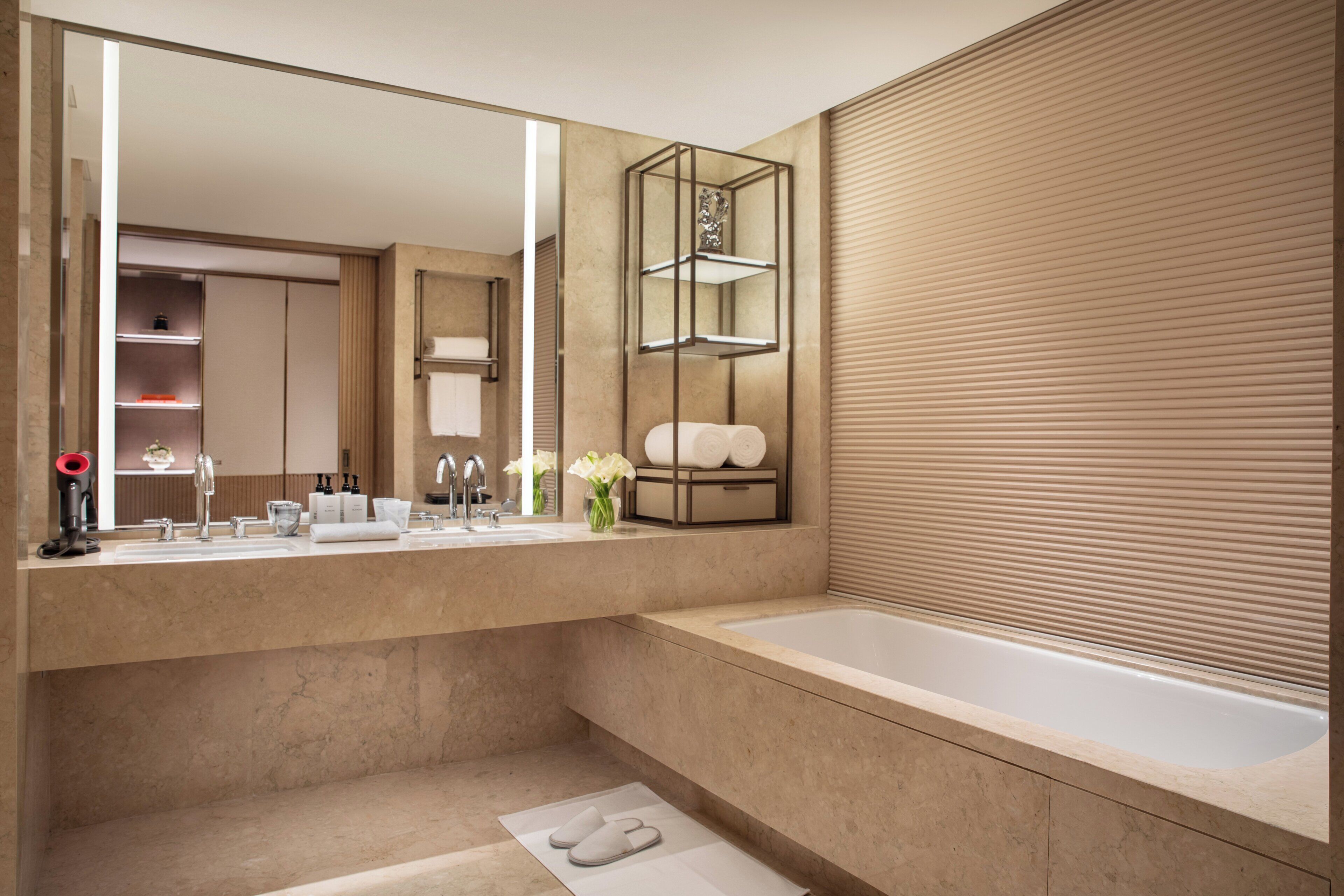 A modern bathroom with a large mirror, a bathtub, and a vanity with a towel rack.