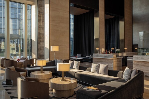 Un hall d’entrée moderne avec des espaces de détente, un bar et une grande fenêtre.