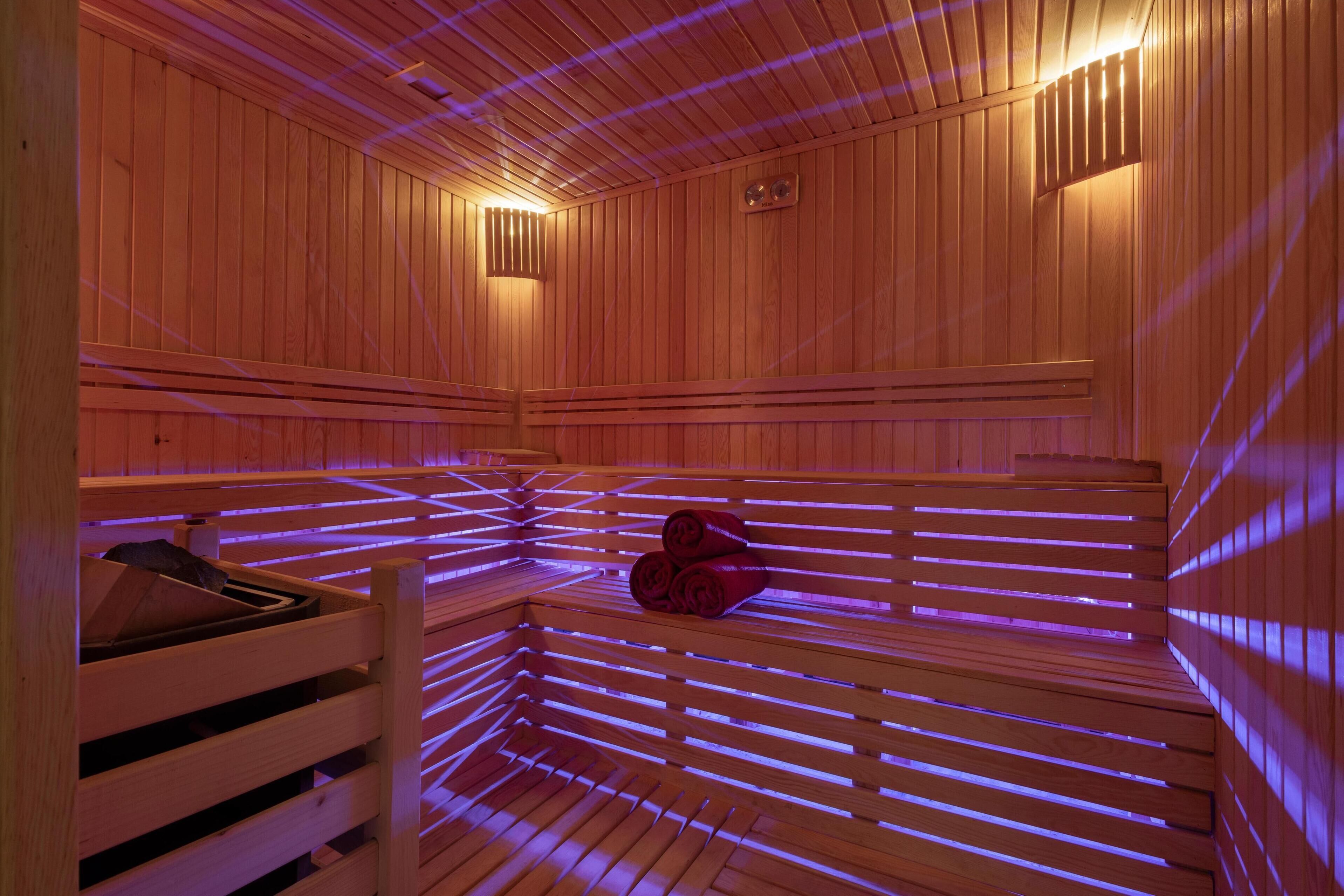 A sauna with wooden benches and slatted walls, equipped with a bench heater and a bench warmer.