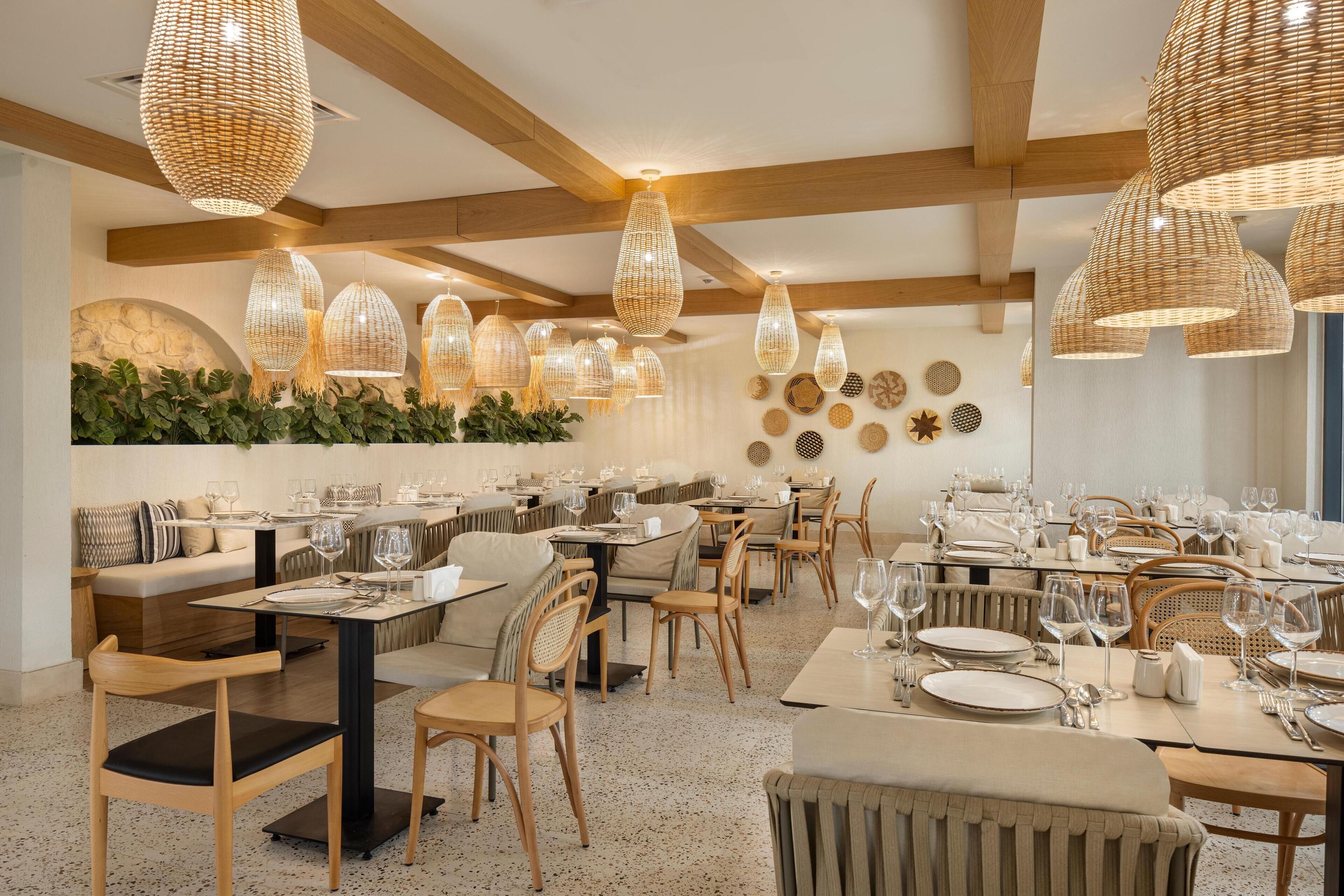 A restaurant with wooden beams, woven pendant lights, and a variety of seating arrangements including tables and booths.