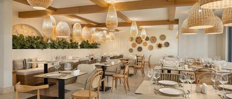 A restaurant with wooden beams, woven pendant lights, and a variety of seating arrangements including tables and booths.