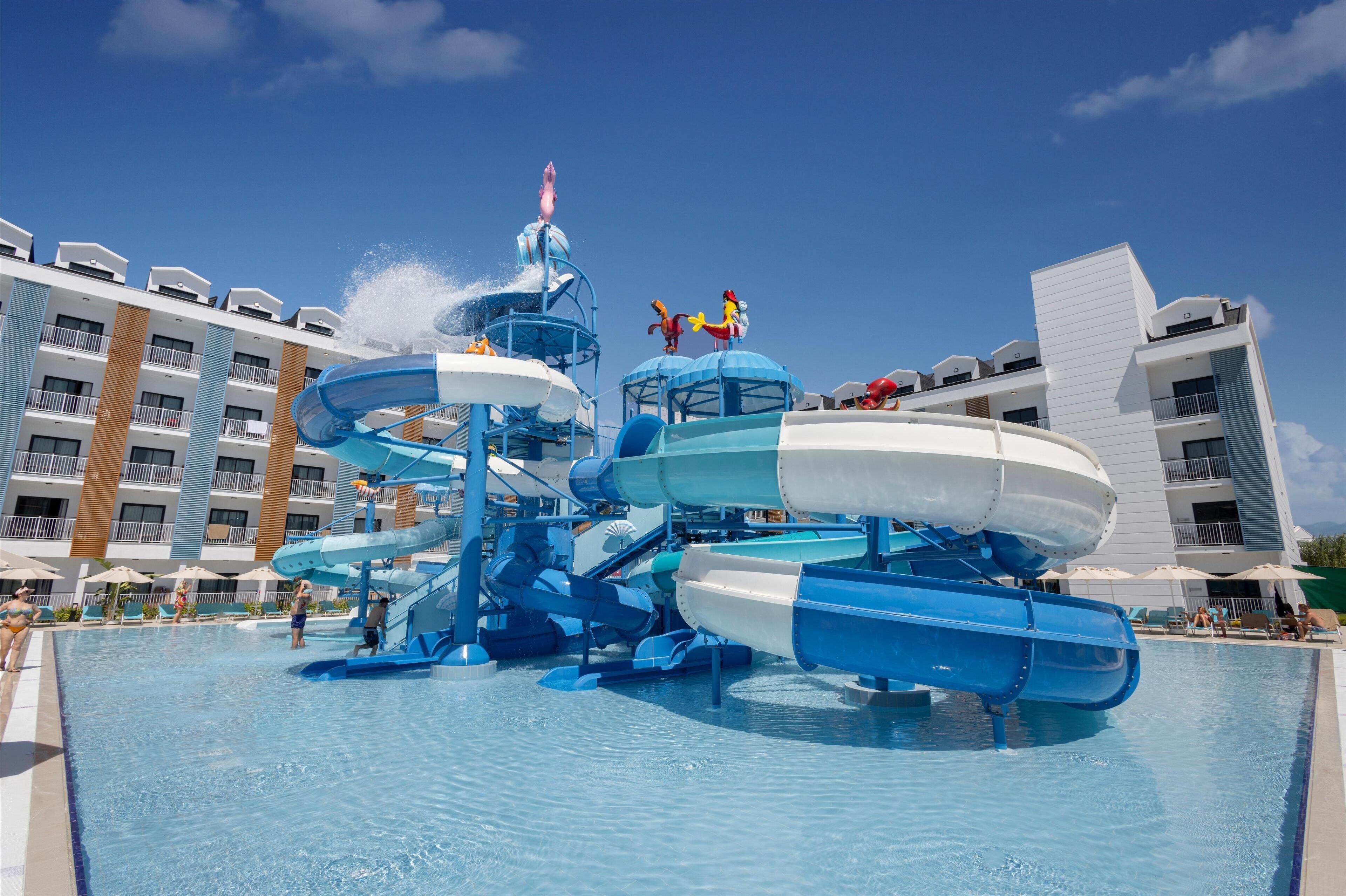 A water park with multiple slides and a pool area, surrounded by hotel buildings.