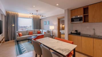 A modern hotel room with a living area, dining space, and kitchen.