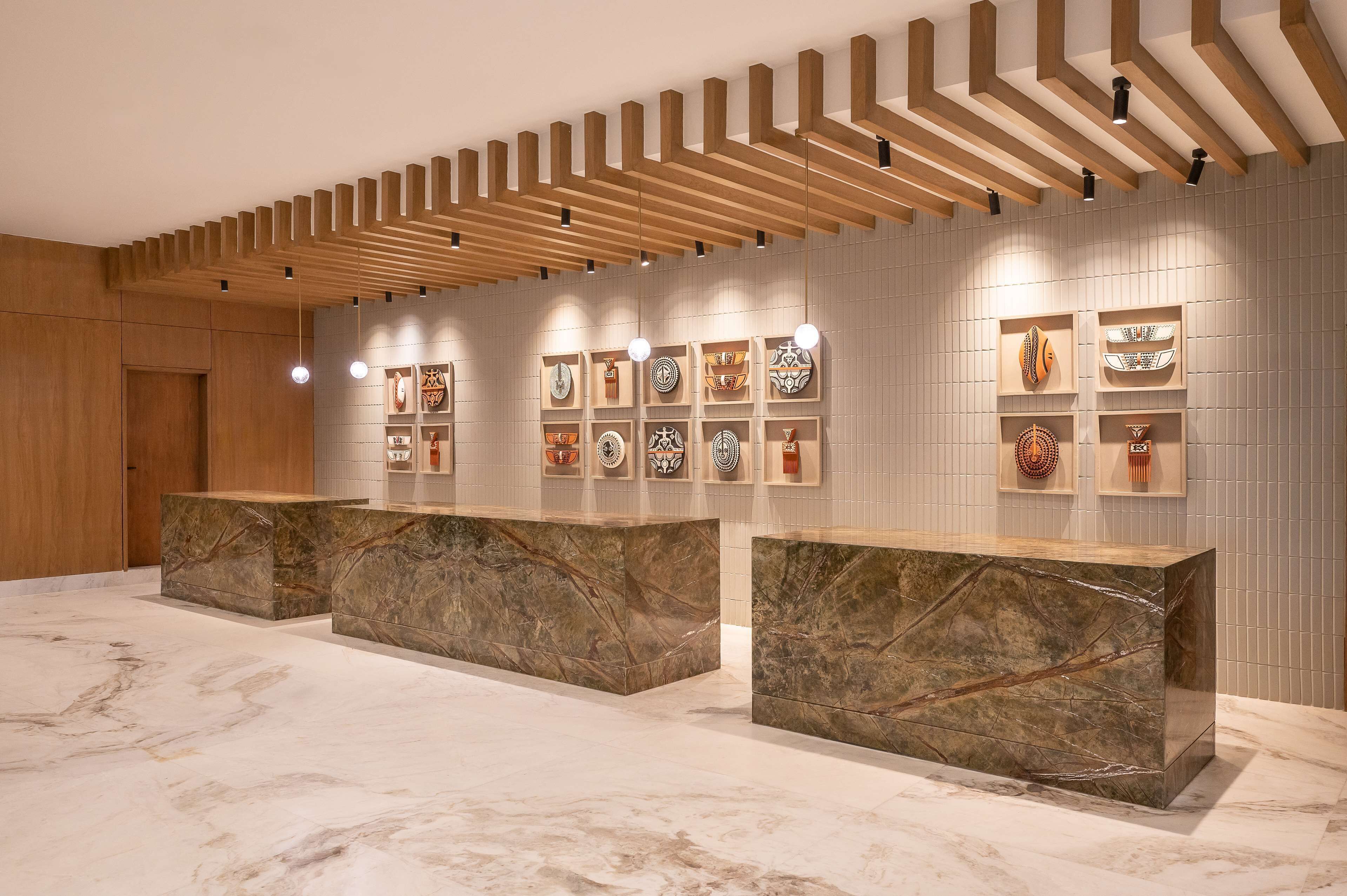 A reception area with marble counters, wooden slatted ceiling, and wall-mounted decorative plates.