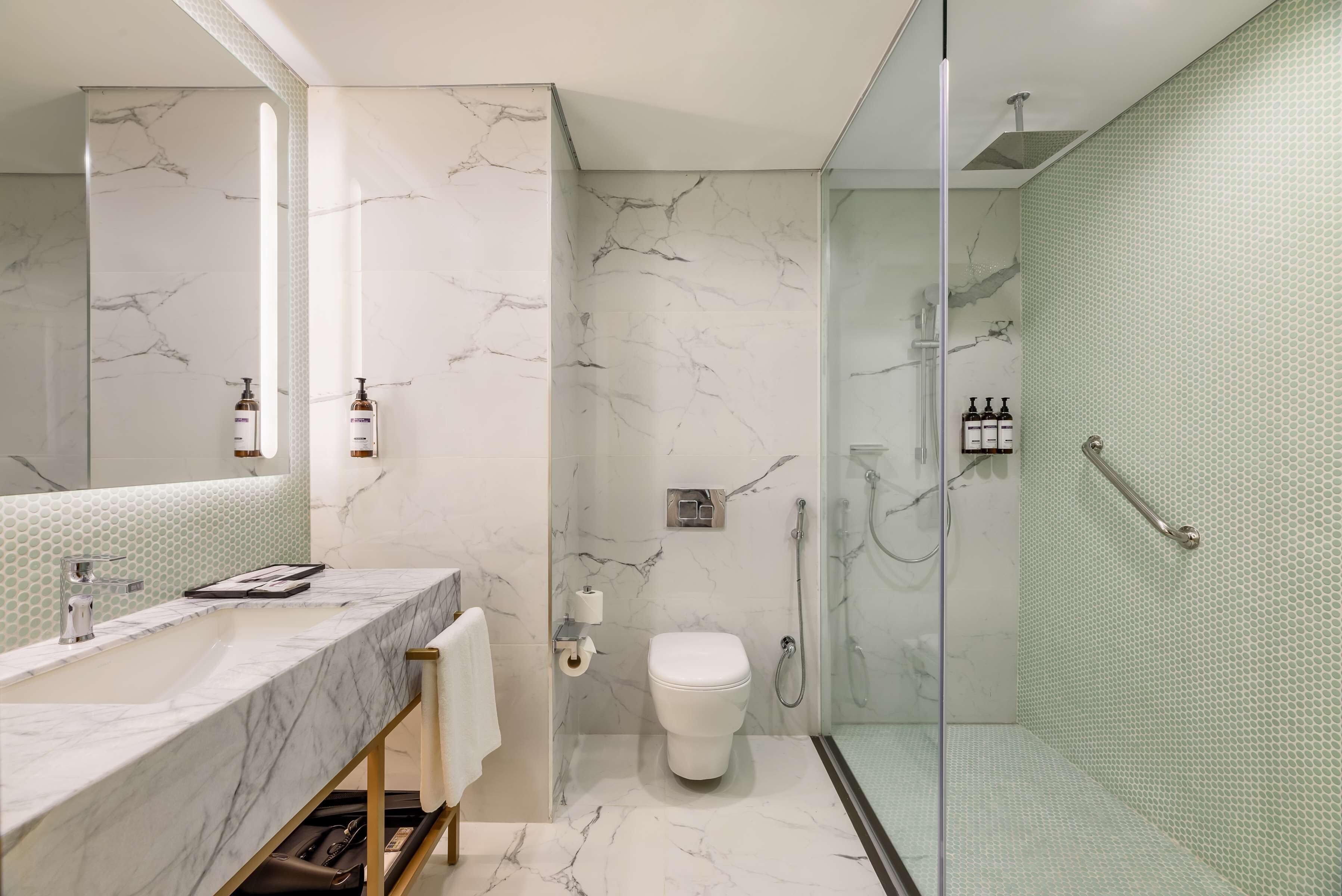 Une salle de bain moderne avec un meuble-lavabo en marbre, des toilettes et une douche séparée par une paroi en verre.
