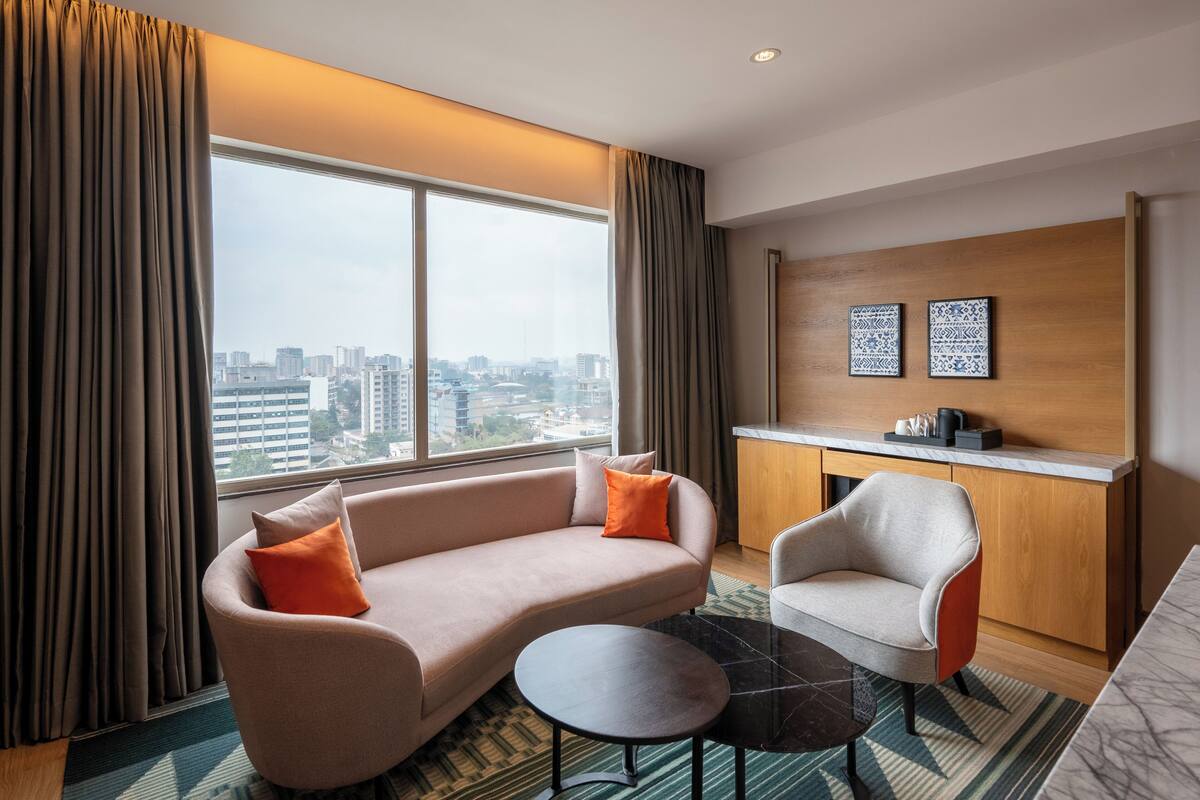 A modern hotel room with a sofa, armchair, and a small table.