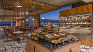 Zona de buffet con diferentes opciones de comida y vistas a montañas a través de amplios ventanales.