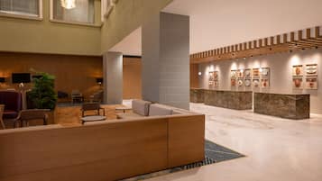 Un vestíbulo moderno con mostrador de recepción de madera, zona de estar y una exhibición de objetos decorativos.