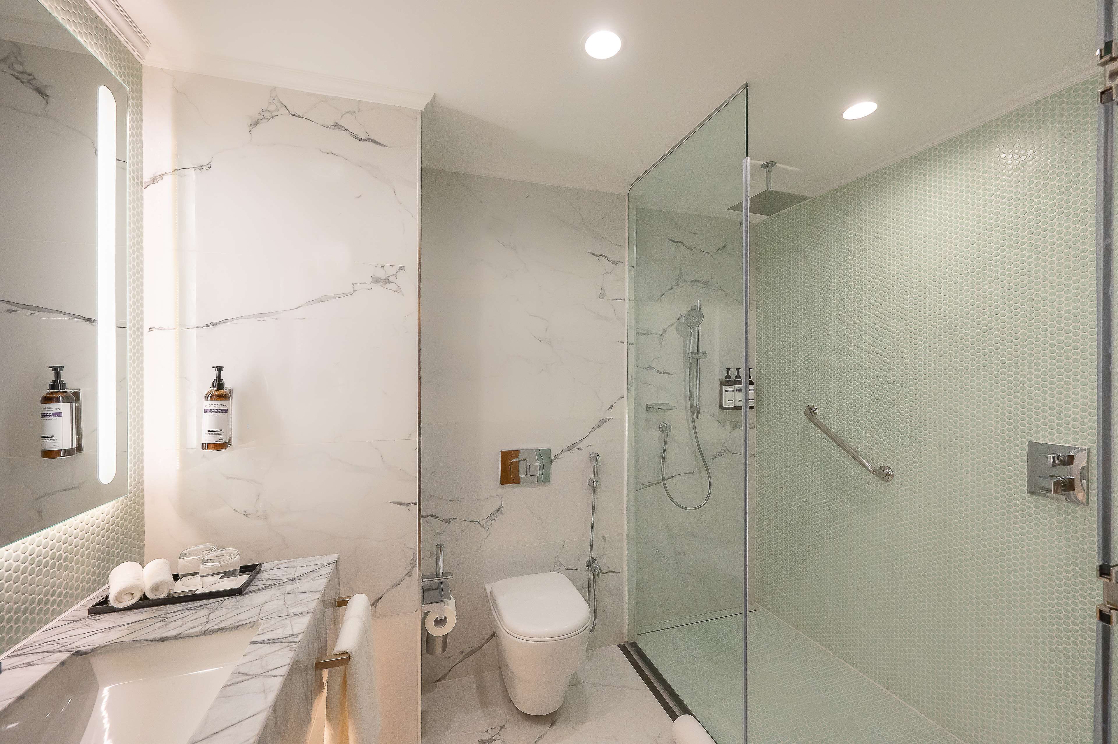 Une salle de bain moderne avec un meuble-lavabo en marbre, une douche à parois de verre et des toilettes.