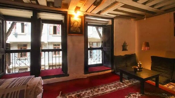 Una habitación acogedora con alfombra roja, un sofá, una mesa con lámpara y vistas a un balcón por la ventana.