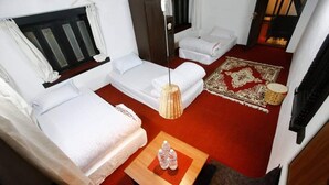 Habitación compacta con dos camas, una mesita con botellas de agua, alfombra roja y un tapete decorativo.