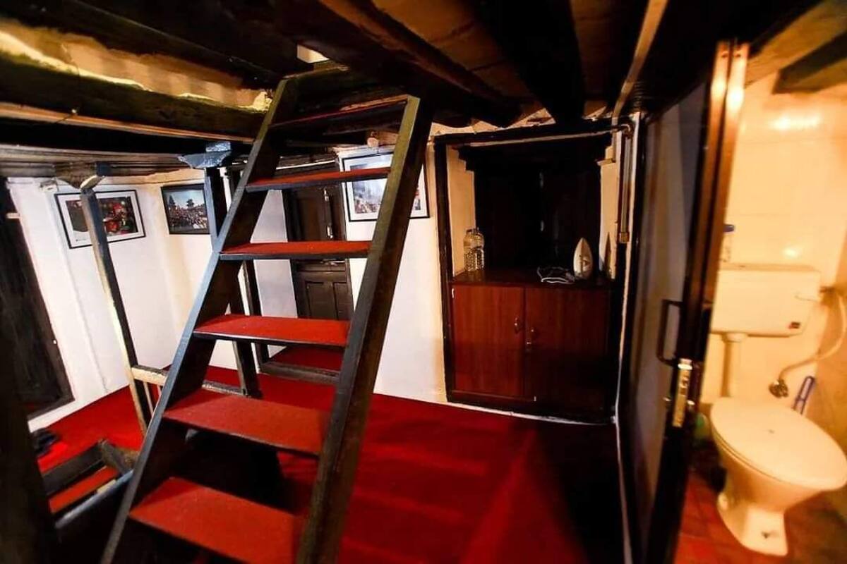 A narrow staircase leading to a small room with a wooden cabinet and a toilet.