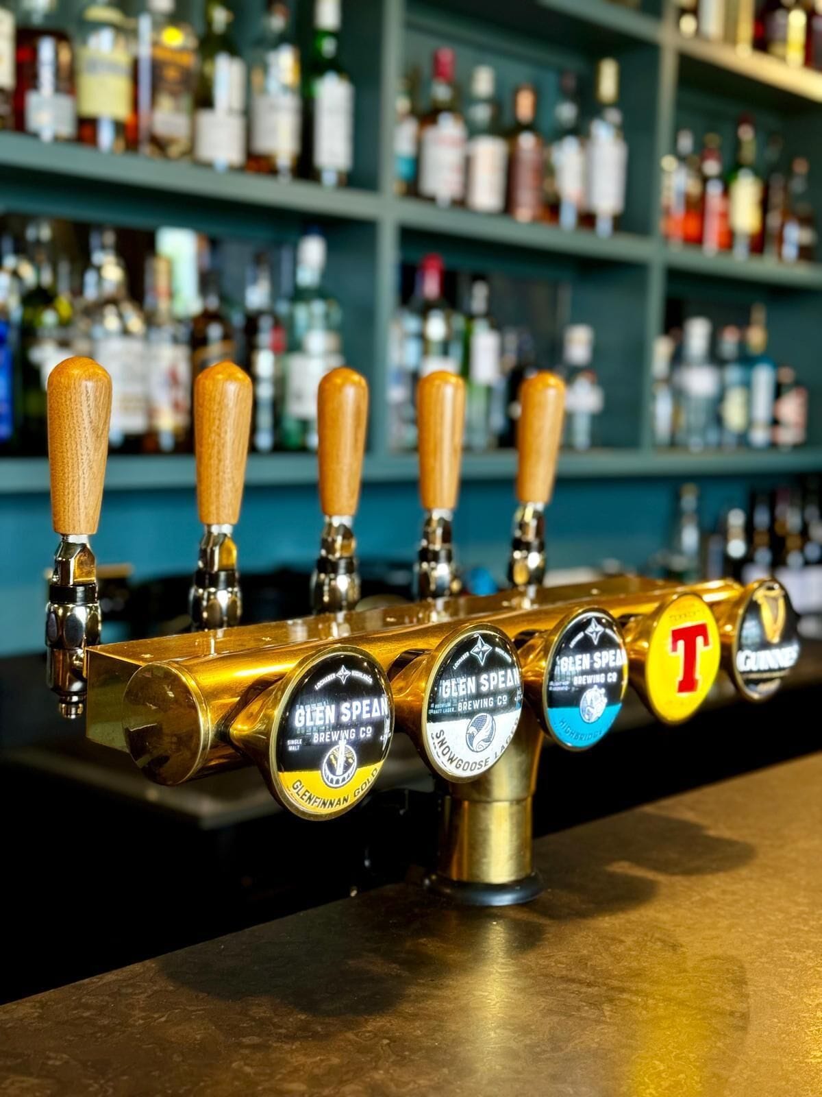 A bar with multiple taps, each labeled with different beer brands.