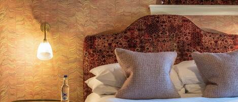 A hotel room with a bed, a nightstand, a lamp, and two framed pictures on the wall.