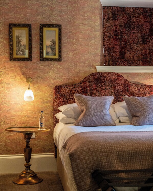 Una habitación de hotel con una cama, una mesita de noche, una lámpara y dos cuadros en la pared.