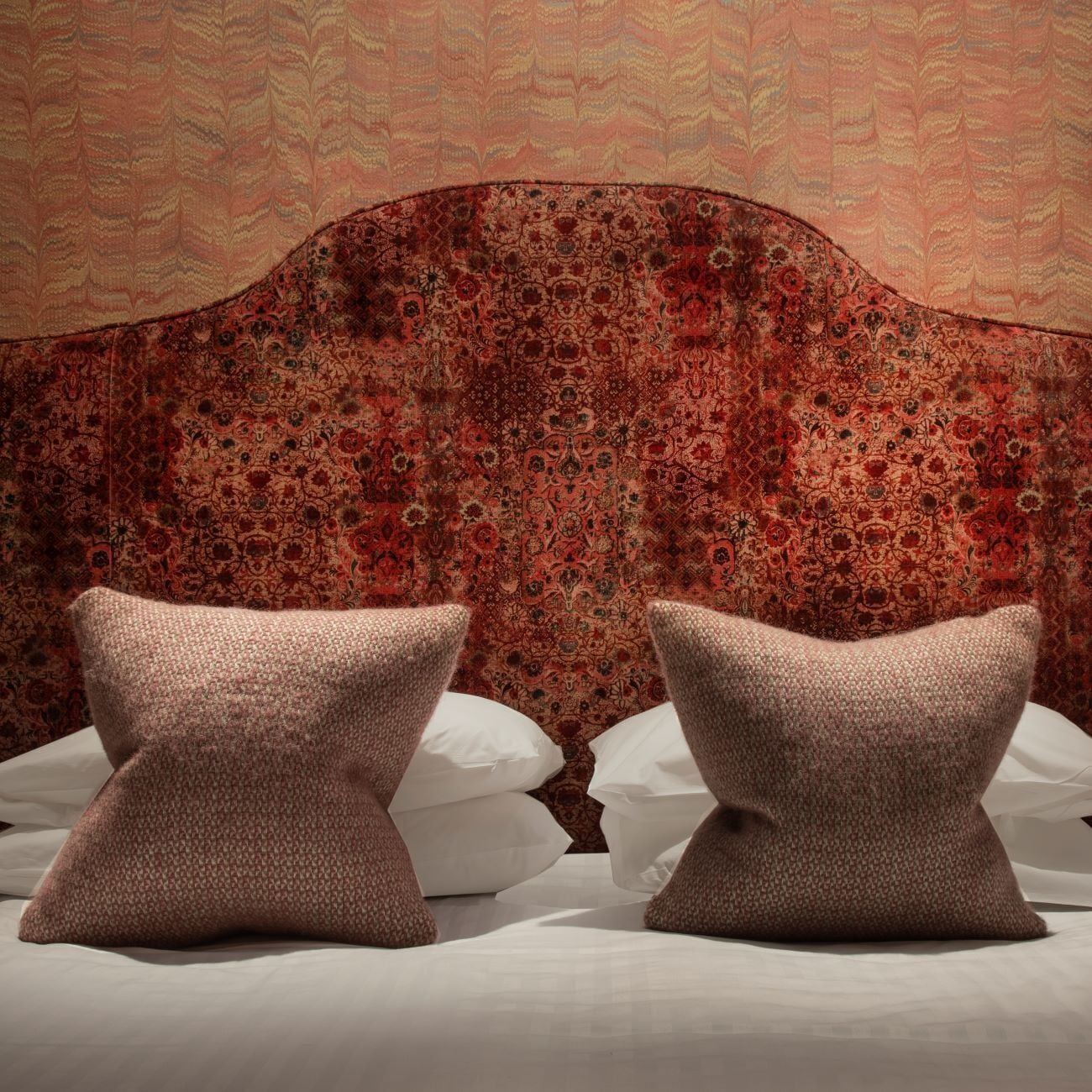A bed with two pillows and a headboard with a floral pattern.