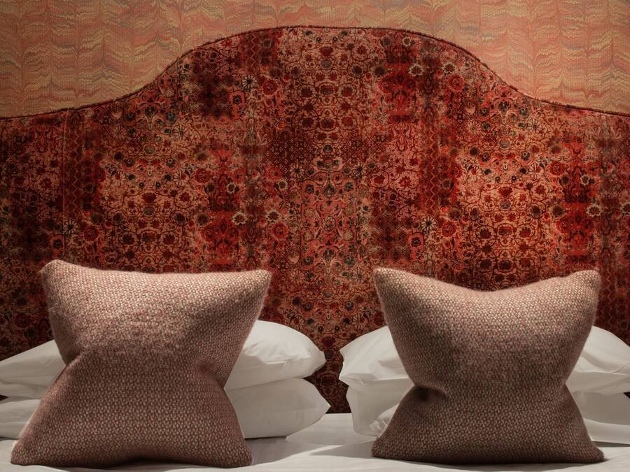 A bed with two pillows and a headboard with a floral pattern.