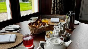 Una mesa de desayuno dispuesta con té, café, croissants y una cesta de pasteles.