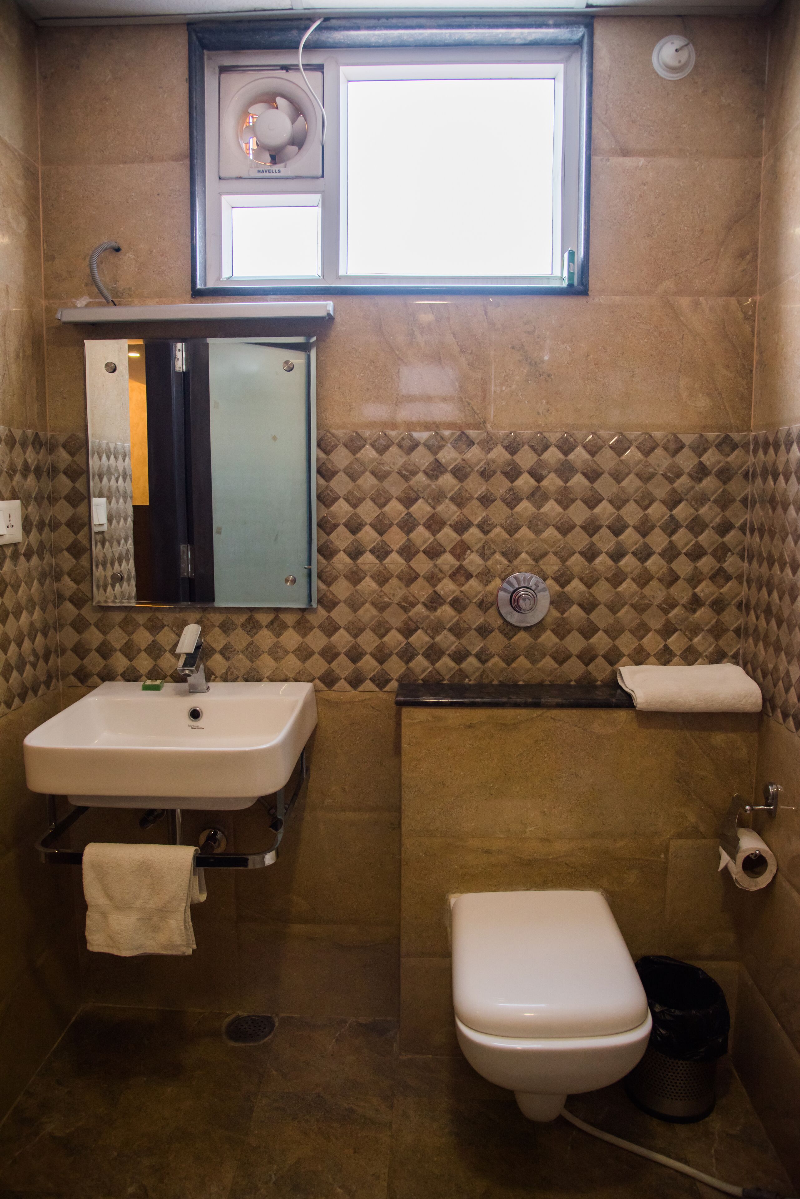 Ein Badezimmer mit Waschbecken, Spiegel, Toilette und einem Fenster über der Toilette.